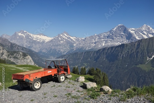 panoramic view of swiss alpine mountains and lush vegetation in summer with truck and snow mountains in background. Eiger and Moench mountains.