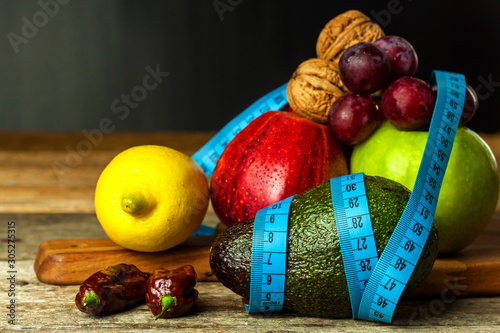 Concept diet. Healthy food. Fruits on a wooden board wrapped with measuring tape on a wooden table. Weigh loss concept.