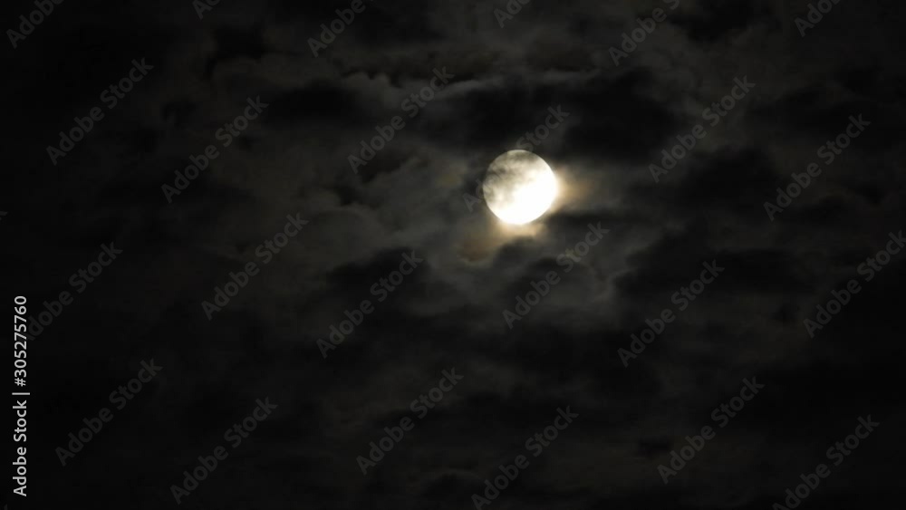 Full moon at night with cloud real time. 4k video full moon in the black sky.  Clouds passing by moon at night. night sky with cloudy weather