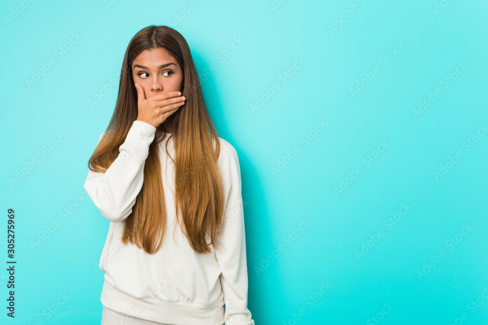 Young slim woman thoughtful looking to a copy space covering mouth with hand. Young slim woman thoughtful looking to a copy space covering mouth with hand.