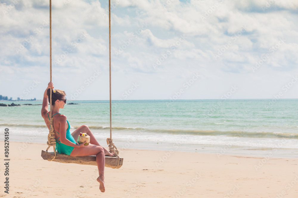 Beautiful woman swinging at tropical beach in Khao Lak region. Thailand, Asia