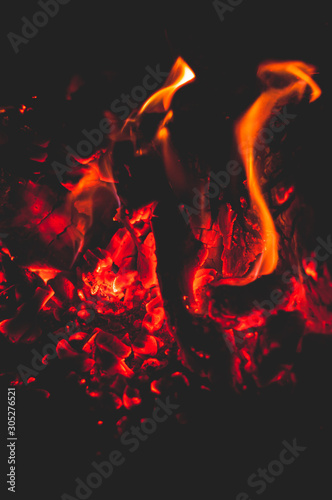 Fiery red-hot coals on black background. Close-up.