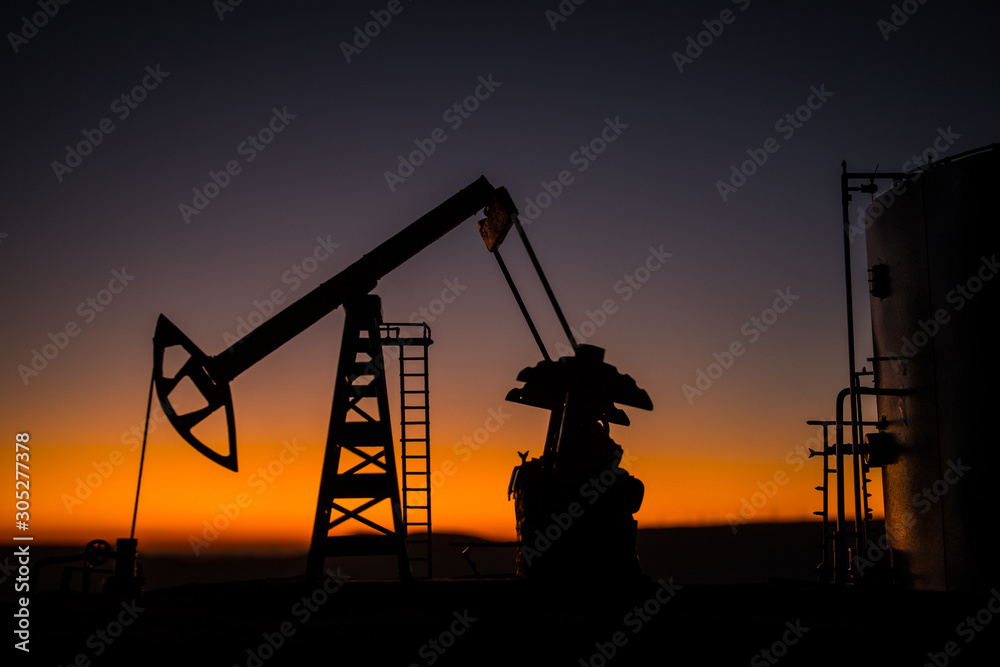 Creative artwork decoration. Oil pump and oil refining factory at sunset. Energy industrial concept. Selective focus.