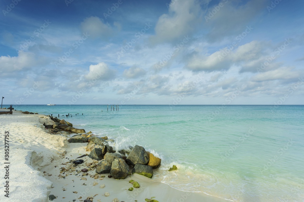 Fototapeta premium White sand beach and turquoise waves. Turquoise sea water and blue sky. Eagle Beach of Aruba Island. Beautiful backgrounds.
