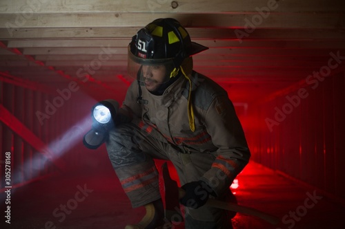 Fire fighter in crawl space shinging light photo