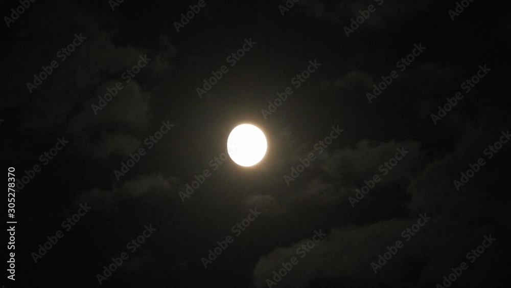 Full moon at night with cloud real time. 4k video full moon in the black sky.  Clouds passing by moon at night. night sky with cloudy weather