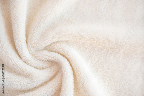 Soft cozy plaid made of white fabric with a pile lies in beautiful folds