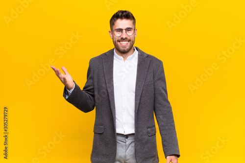 young handosme man feeling happy, surprised and cheerful, smiling with positive attitude, realizing a solution or idea against flat color wall photo