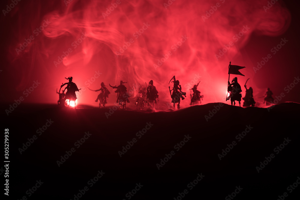 Medieval battle scene with cavalry and infantry. Silhouettes of figures as separate objects, fight between warriors on dark toned foggy background. Night scene. Medieval battle scene with cavalry and infantry. Silhouettes of figures as separate objects, fight between warriors on dark toned foggy background. Night scene.