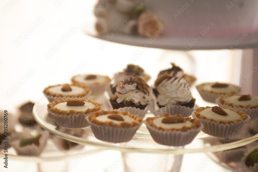 Plate with sweet cakes on pink table against brick wall background Plate with sweet cakes on pink table against brick wall background