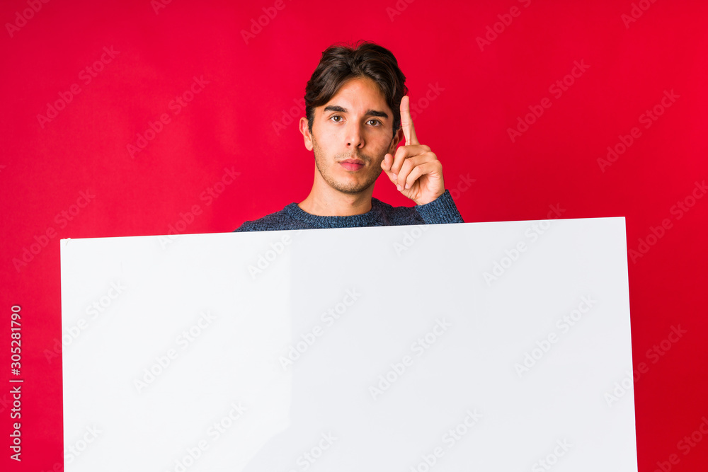 Young man holding a placard showing number one with finger. Young man holding a placard showing number one with finger.