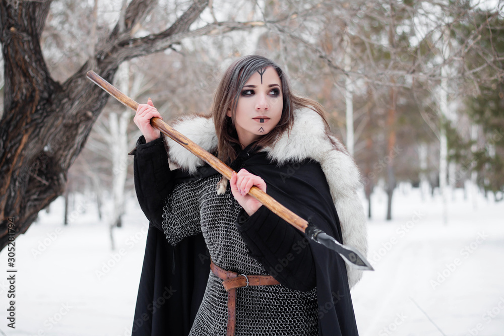 The woman is a medieval warrior of the Viking Age in the winter in the  forest.