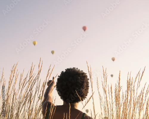 chica afro observando globos aerostaticos como vuelan photo