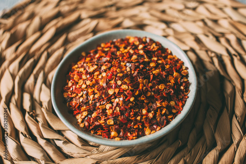 Heap of chili flakes in a bowl. Red cayenne pepper close up.   photo
