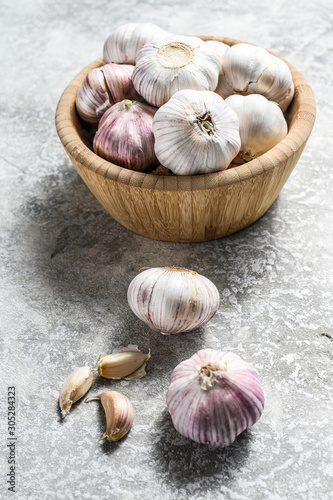 Garlic Cloves and Bulb in vintage wooden bowl. Gray background. Top view