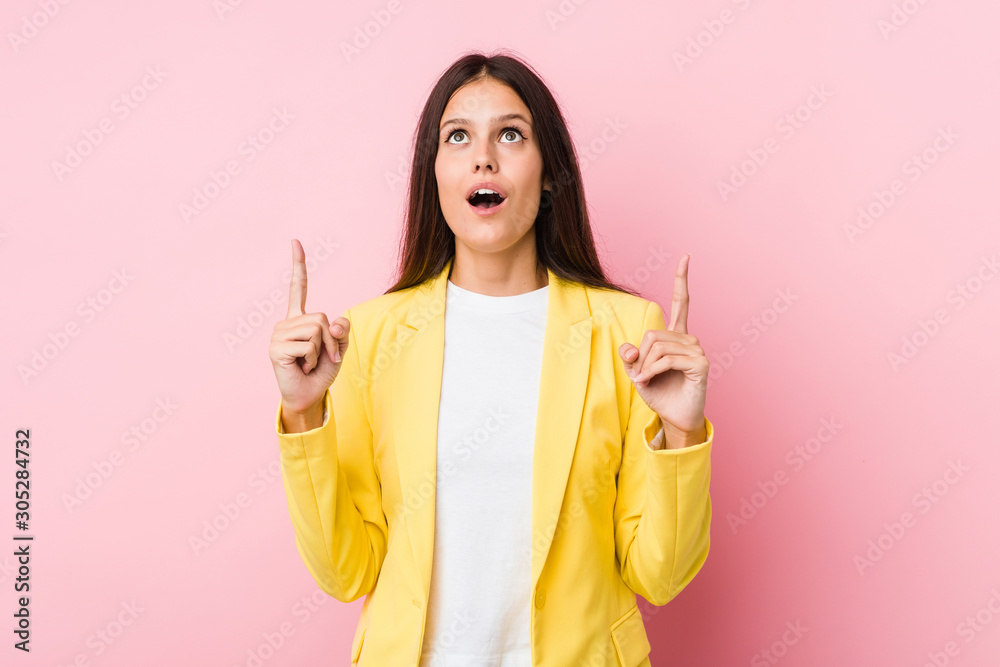 Young business woman pointing upside with opened mouth. Young business woman pointing upside with opened mouth.