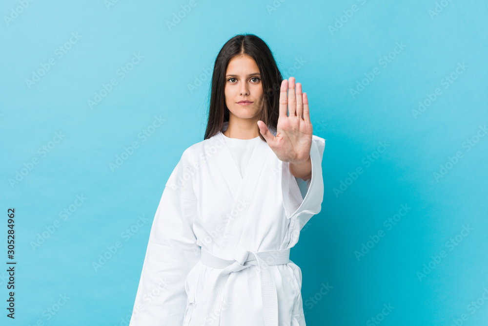 Young karate woman standing with outstretched hand showing stop sign, preventing you. Young karate woman standing with outstretched hand showing stop sign, preventing you.