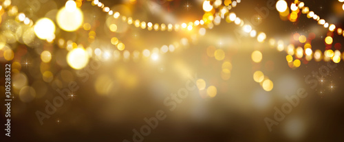 Christmas Gold glowing Background. Golden Holiday Abstract Glitter Defocused Backdrop With Blinking Stars and garlands. Tinsel Blurred gold Bokeh on black background. Festive defocused elegant border