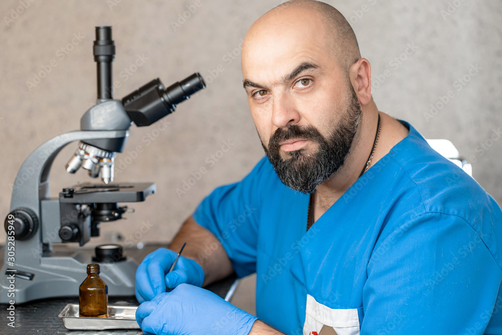 Male laboratory assistant examining biomaterial samples in a microscope Male laboratory assistant examining biomaterial samples in a microscope