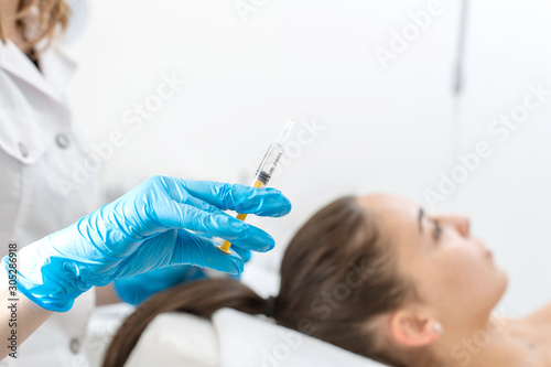 Close-up  the beautician makes injections of vitamins into the scalp for strengthening the hair.