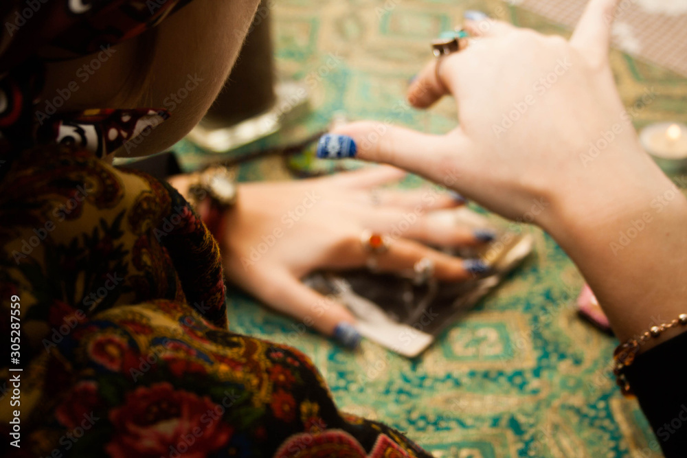 Obraz premium Gypsy psychic looking for a man in a photo using a pendulum. Love spell on photos