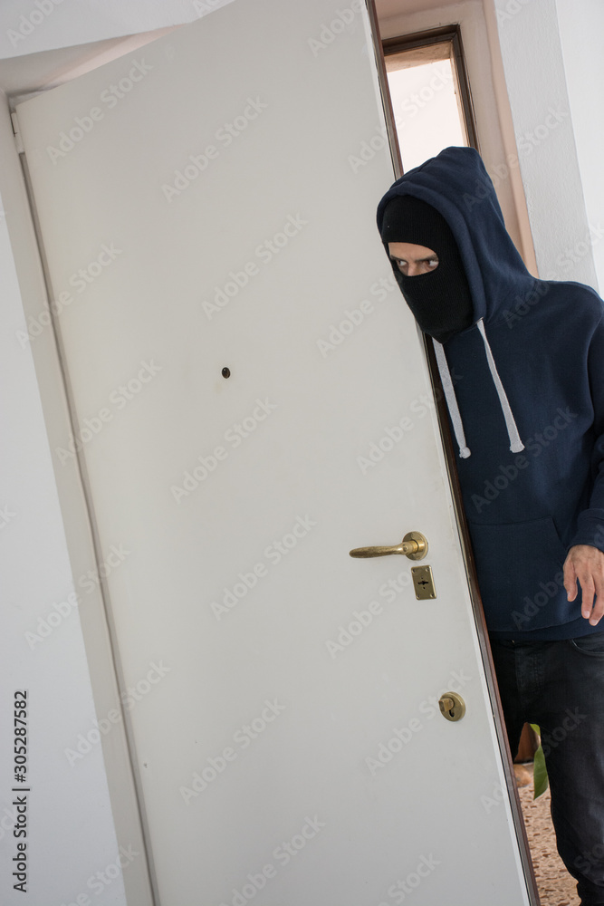 Masked thief enters a house to steal. Concept of lack of security for citizens