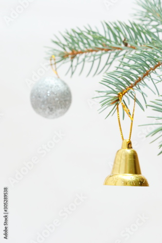 Merry christmas and a happy new year! The atmosphere of the winter holidays. Green spruce branch with decorations on a light background and free space for an inscription.