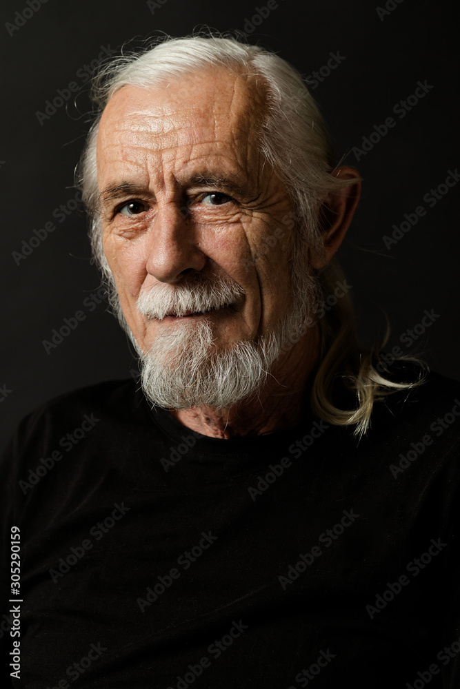 Low key studio portrait of beautiful gray hair old man looking at the camera. Vertically