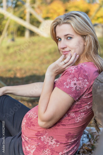 Portrait of cool attractive young woman sitting outdoors. Woman is looking at camera supporting her chin by fingers. Vertically.
