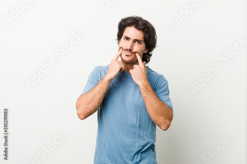 Young handsome man against a white background doubting between two options.