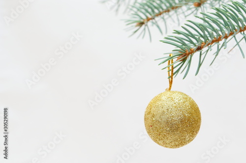 Merry christmas and a happy new year! The atmosphere of the winter holidays. Green spruce branch with decorations on a light background and free space for an inscription.