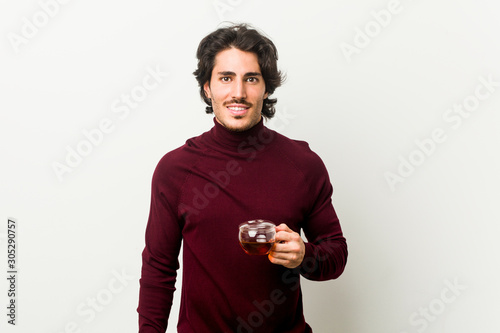 Young man holding a tea cup happy, smiling and cheerful.