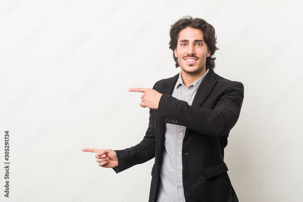 Young business man against a white background excited pointing with forefingers away. Young business man against a white background excited pointing with forefingers away.
