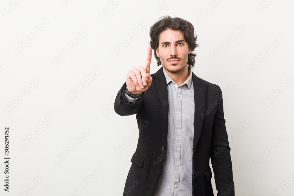 Young business man against a white background showing number one with finger. Young business man against a white background showing number one with finger.