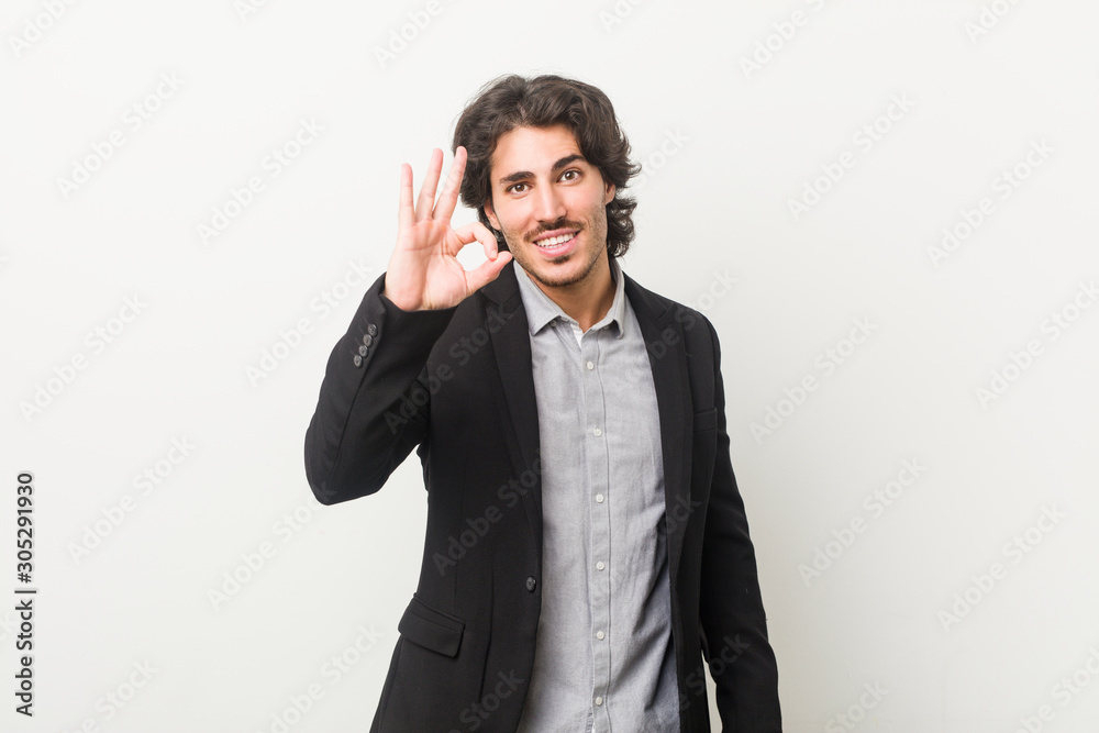Young business man against a white background cheerful and confident showing ok gesture. Young business man against a white background cheerful and confident showing ok gesture.