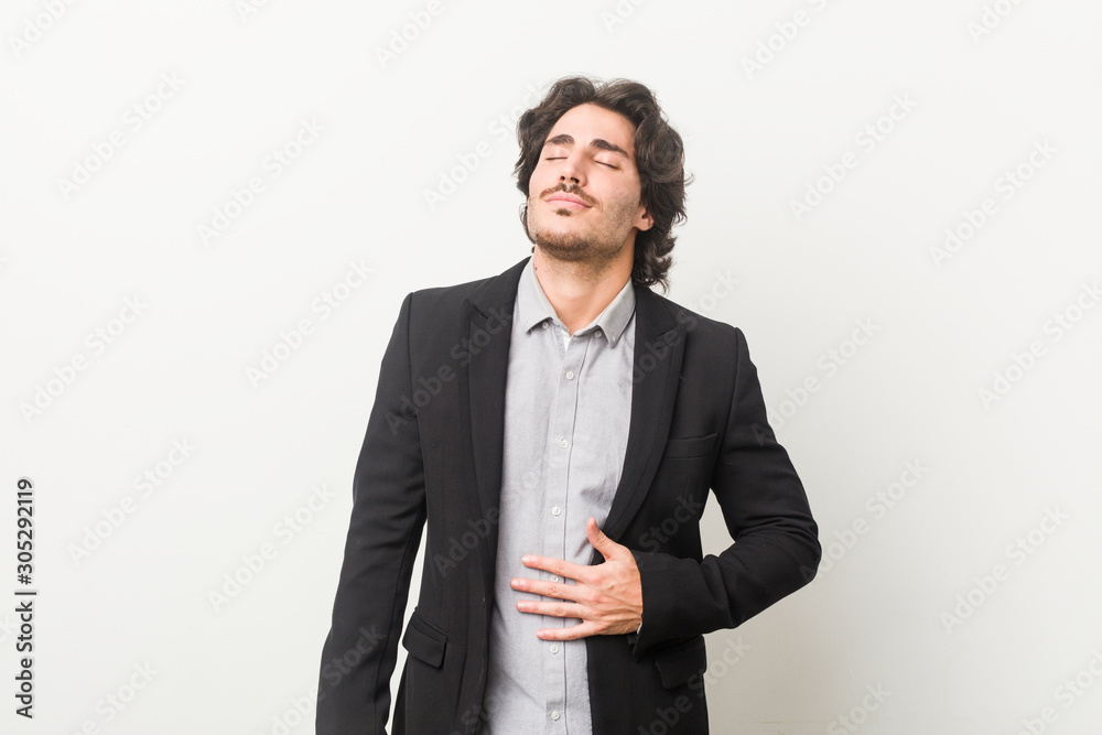 Young business man against a white background touches tummy, smiles gently, eating and satisfaction concept. Young business man against a white background touches tummy, smiles gently, eating and satisfaction concept.