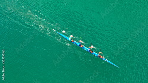 Aerial drone top down photo of fit women competing in sport canoe in tropical exotic lake with emerald waters