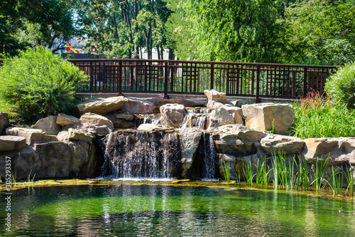 Wooden bridge over a small river waterfall, green river and grass in kiev zoo in ukraine