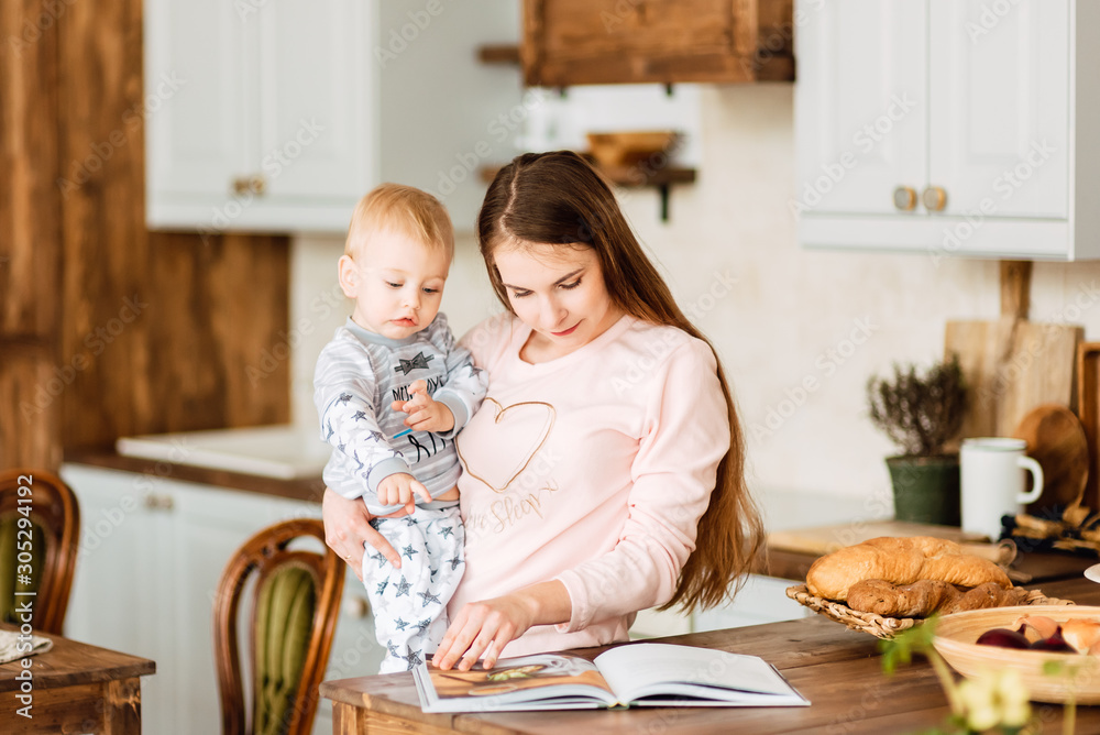 Young mother and son are playing in the kitchen of their home. Cute boy with his mom. Happy and cute family chatting with a baby Young mother and son are playing in the kitchen of their home. Cute boy with his mom. Happy and cute family chatting with a baby