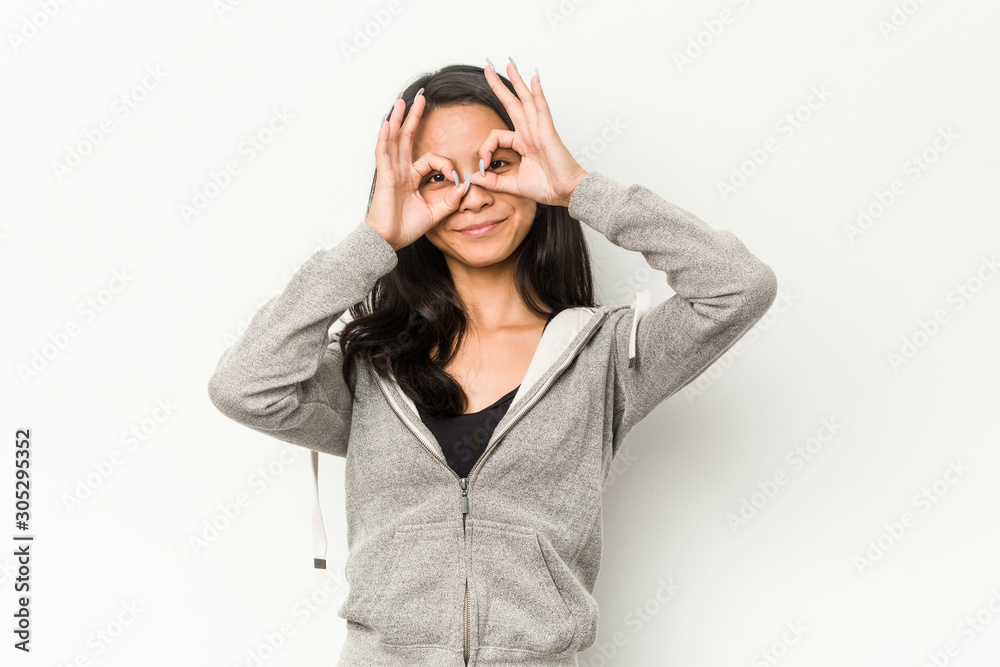 Young fitness chinese woman showing okay sign over eyes Young fitness chinese woman showing okay sign over eyes
