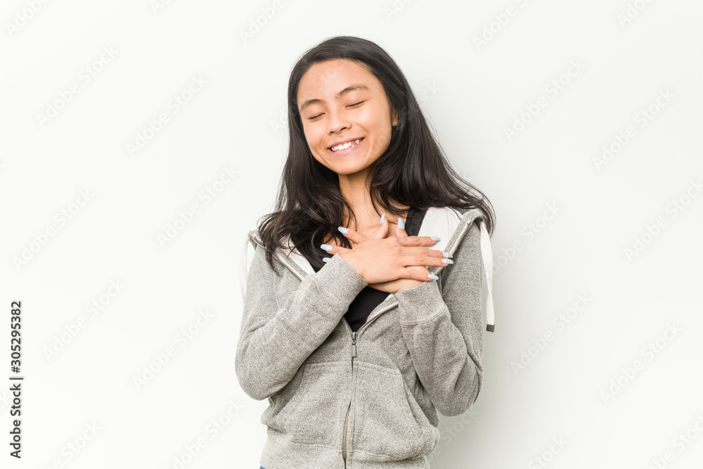 Young fitness chinese woman laughing keeping hands on heart, concept of happiness. Young fitness chinese woman laughing keeping hands on heart, concept of happiness.