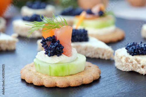 Valokuva Assorted party buffet, finger food with with smoked salmon and caviar over black