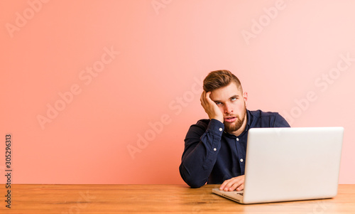 Young man working with his laptop who is bored, fatigued and need a relax day. photo