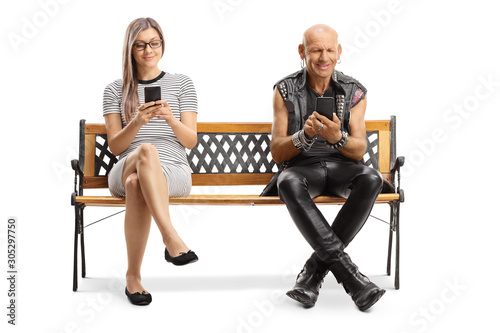 Young woman and a punker with mobile phones sitting on a bench