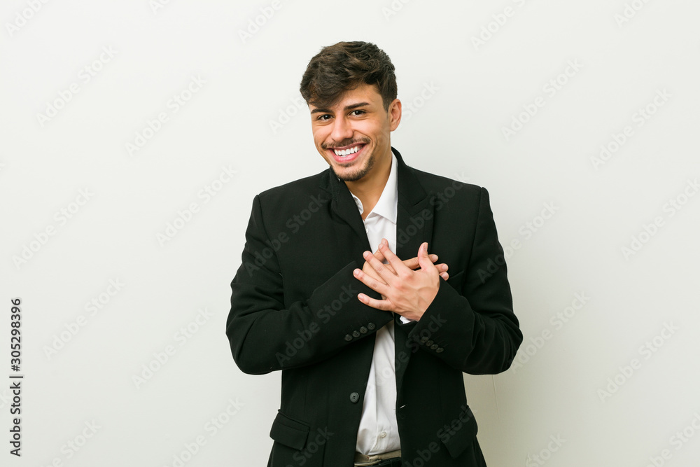 Young business hispanic man has friendly expression, pressing palm to chest. Love concept.