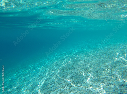 White stones under turquoise water in the sea.