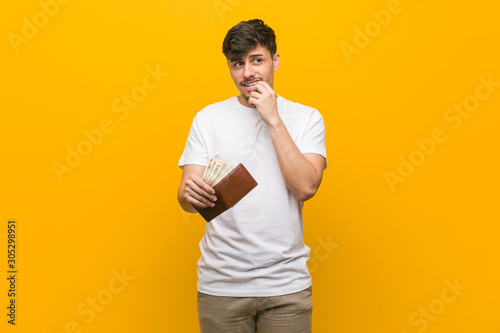 Young hispanic man holding a wallet relaxed thinking about something looking at a copy space.