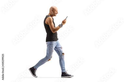 Bald male hispter walking and holding a mobile phone