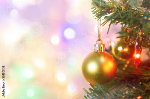 Christmas decoration. Hanging gold balls on pine branches Christmas tree garland and ornaments over abstract bokeh background with copy space.