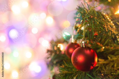 Christmas decoration. Hanging red balls on pine branches Christmas tree garland and ornaments over abstract bokeh background with copy space.